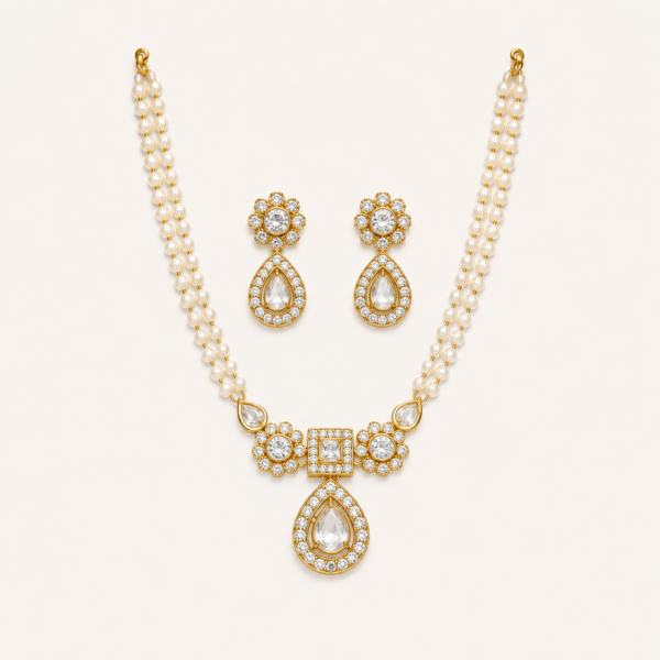 This pearl necklace set for women features elegant double-layer strands, a floral centre arrangement and a graceful teardrop drop. Its polished gold finish and coordinated earrings make it a refined choice for weddings, festive functions and family celebrations. Product Highlights Complete necklace set with matching teardrop earrings Double-layer pearl-like strands create a graceful neckline Floral side motifs add symmetry around the central design Square-cut centre detail gives the necklace a structured focal point Teardrop lower section adds elegant movement and visual length Suitable for weddings, festive occasions, receptions and traditional functions Material & Finish This pearl necklace set is crafted from Premium Base Metal and completed with a polished gold finish. The smooth metallic framework complements the pearl-like strands and defines each decorative stone setting. The central section features clean geometric borders, floral detailing and neatly connected elements. The matching earrings carry the same finish and design language, creating a coordinated full-set appearance. No claims are made regarding gold purity, micron plating or anti-tarnish protection. Proper storage and gentle handling are recommended to help maintain the finish. Stone Details The necklace features clear decorative imitation stones arranged in round, square and teardrop shapes. A square-cut centre stone forms the main geometric focus, while round floral clusters create balance on both sides. A larger pear-shaped imitation stone hangs below the centre in a framed teardrop setting. Smaller clear accents surround the main stones, adding controlled sparkle without making the design appear overly heavy. The matching earrings repeat the floral top and teardrop drop seen in the necklace. All stones and pearl-like elements are decorative imitation materials and should not be considered diamonds, precious gemstones or genuine pearls. Necklace Design & Wearability The double-layer pearl strands sit neatly around the neckline and lead into a compact central arrangement. This gives the necklace a fuller look while keeping the design elegant and wearable. The vertical teardrop detail creates a flattering fall at the centre. Coordinated earrings complete the look without competing with the necklace, making the set suitable for extended festive and occasion wear. How to Style Pair this pearl necklace set with silk sarees, embroidered lehengas, anarkalis, festive suits or elegant gowns. Style it with a neat bun and soft makeup for weddings, receptions, festive gatherings and family celebrations. Jewelry Care Store separately in a dry jewelry box or soft pouch Clean gently with a soft, dry cloth Keep away from water and moisture Avoid direct contact with perfume, hairspray and chemicals Availability & Pricing Price and stock availability may vary. Tap the Chat on WhatsApp button to confirm the current price, stock status and ordering details. Pan-India shipping is available. Tap below to chat with us on WhatsApp for price and availability.